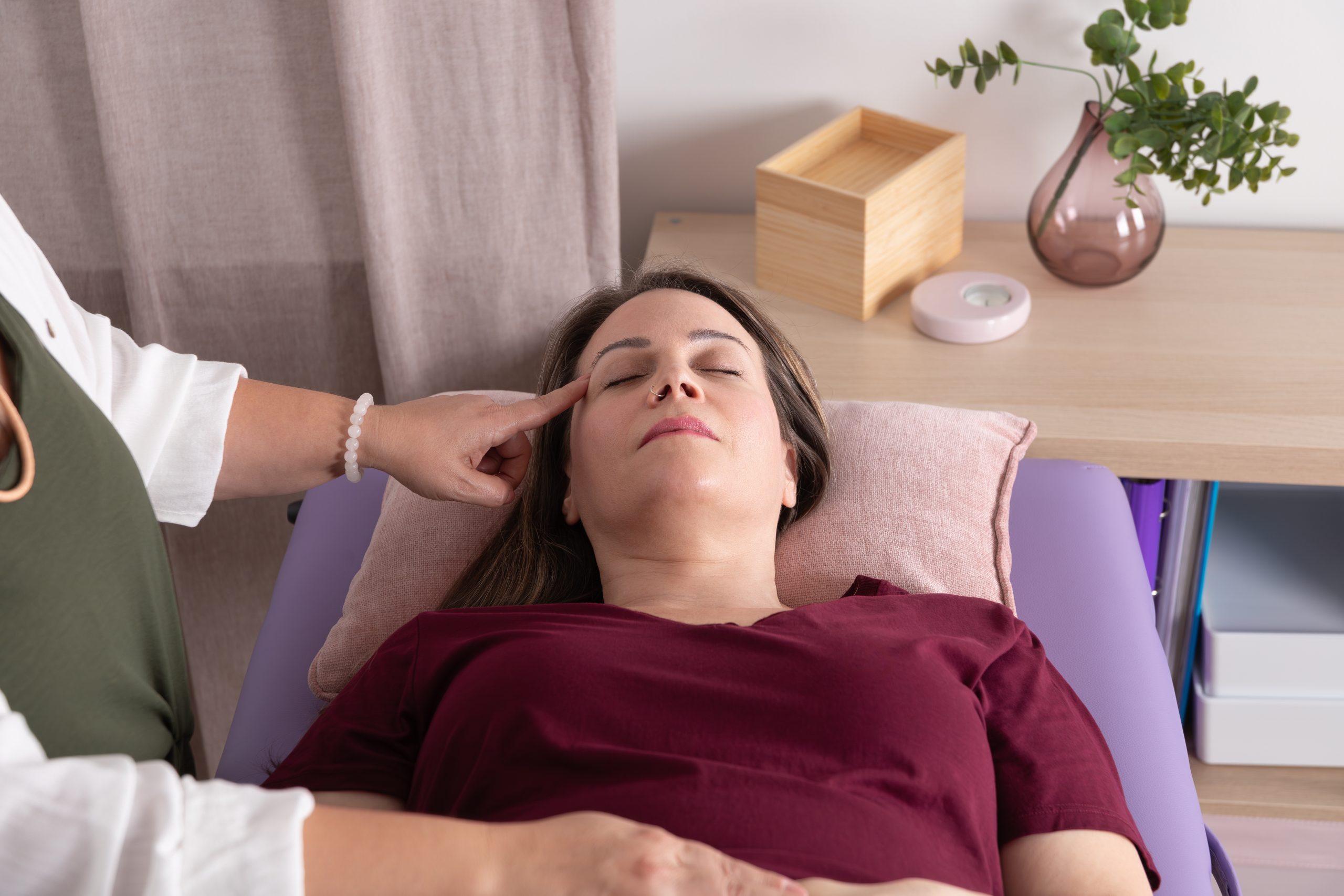 Close-up view from above of a woman with a nose piercing lying on a stretcher in an acupressure session. Concept of therapy, wellness, psychotherapy, kinesiology and acupressure